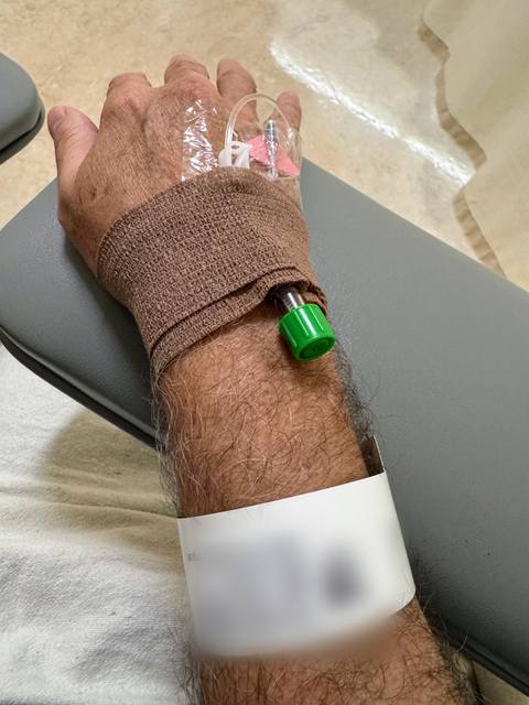 Hand with IV line taped in place and a hospital wristband